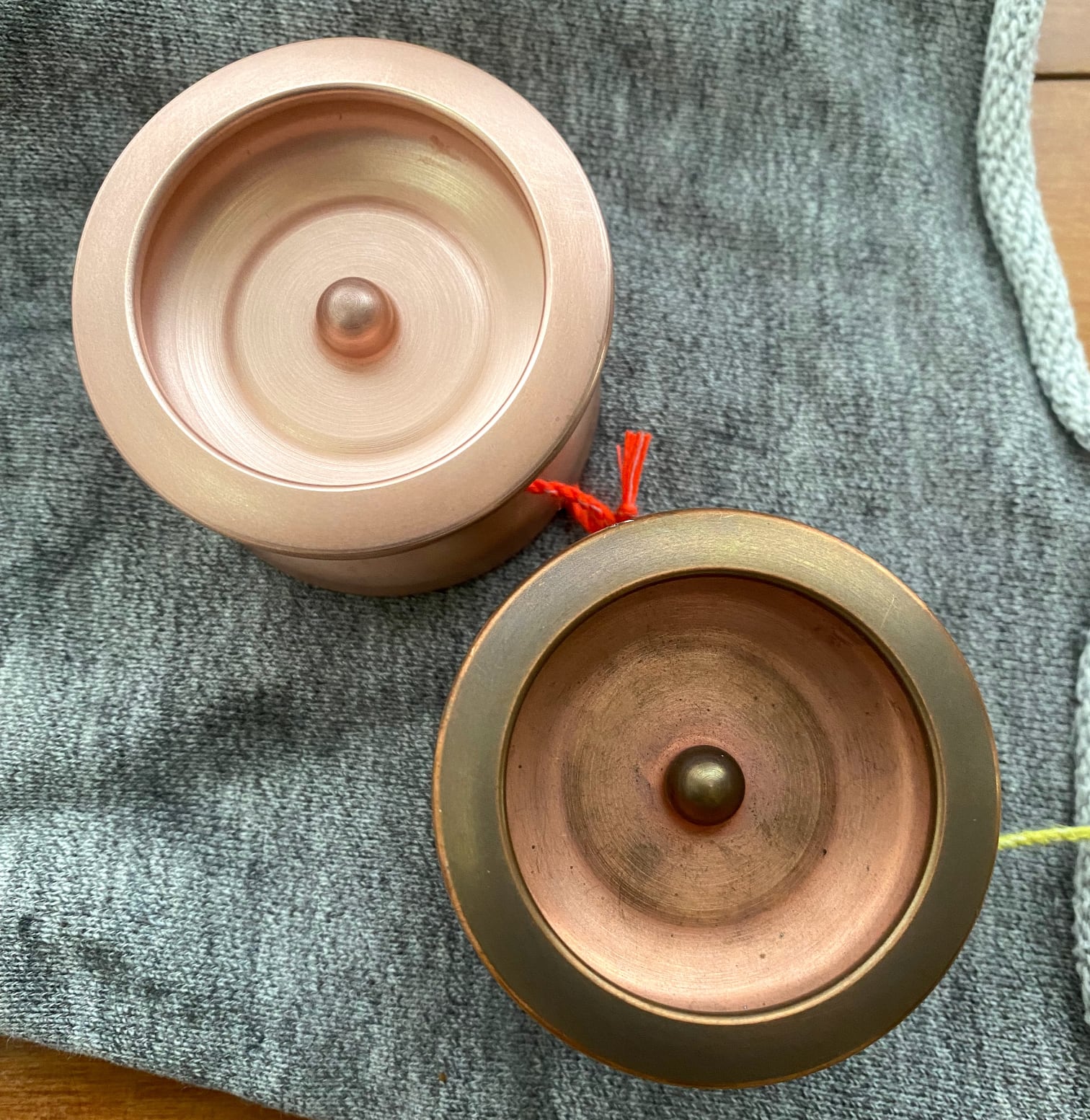Two Copper Theodore yoyos side by side, one is bright and clean, the other has a heavier patina with some darkening and finger prints.